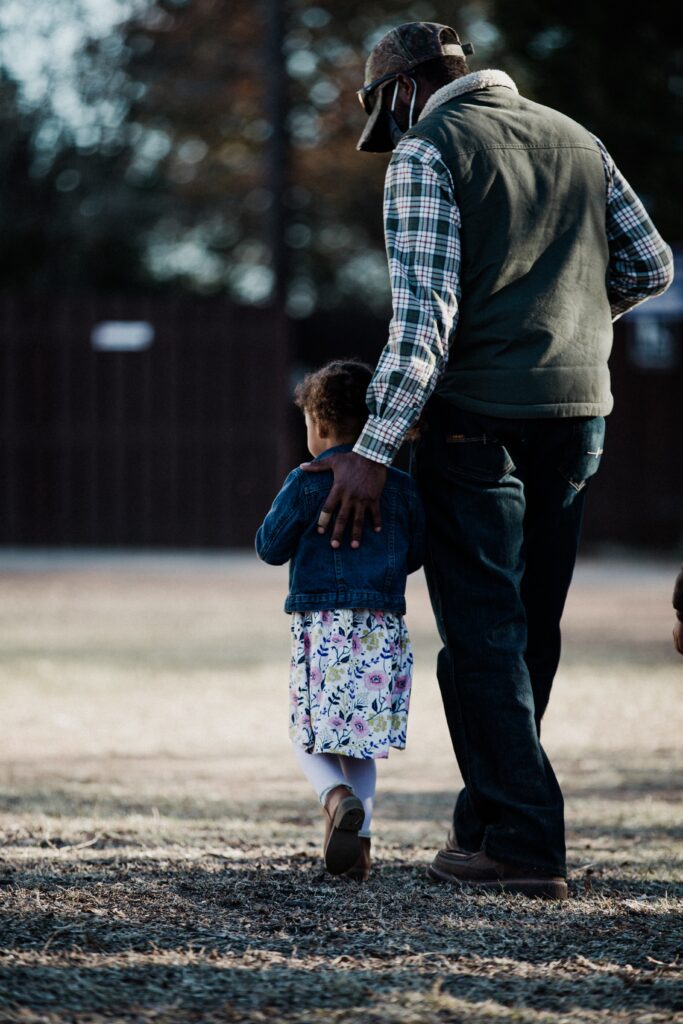 Father and daughter walking on a sunlit path
